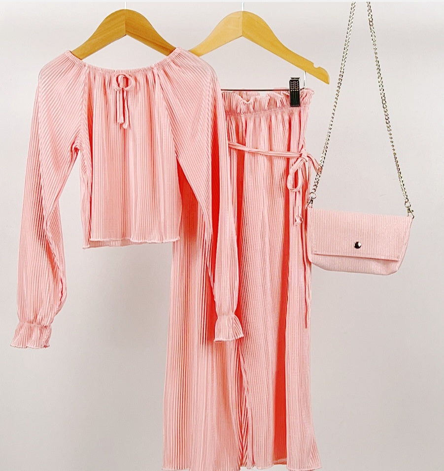 Pink long sleeve pleated top paired with co-ord ruffle waist tie belt wide leg trousers and chain clutch bag.