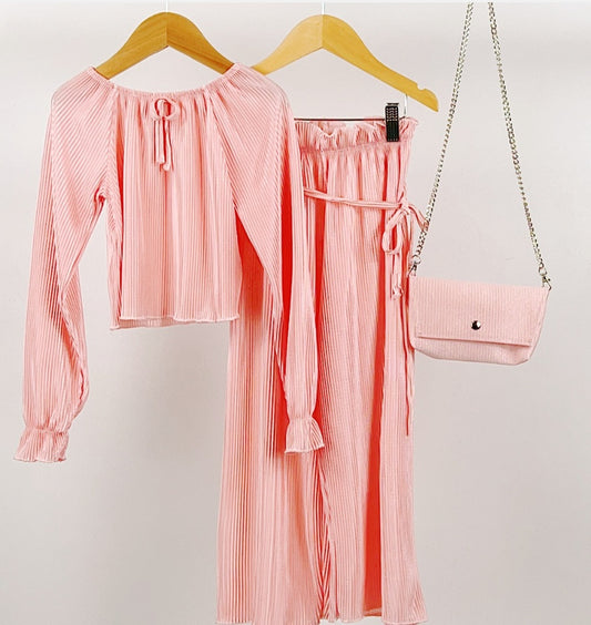 Pink long sleeve pleated top paired with co-ord ruffle waist tie belt wide leg trousers and chain clutch bag.